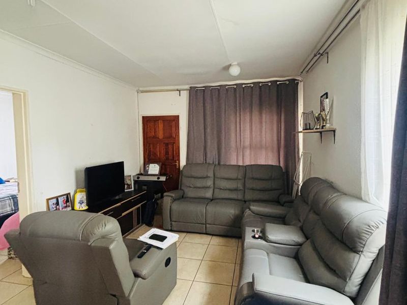A functional living room featuring neutral tiled flooring and curtain rails, providing a blank canvas for potential interior updates.