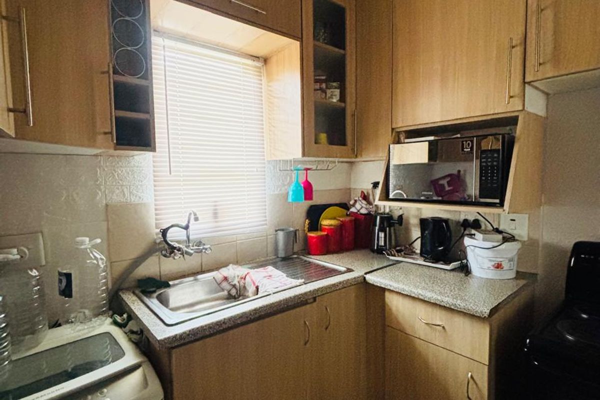 A compact kitchen featuring laminate cabinetry, a stainless steel sink, and a built-in microwave, offering functional storage and preparation space.