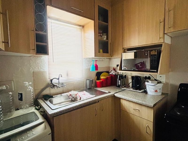 A compact kitchen featuring laminate cabinetry, a stainless steel sink, and a built-in microwave, offering functional storage and preparation space.