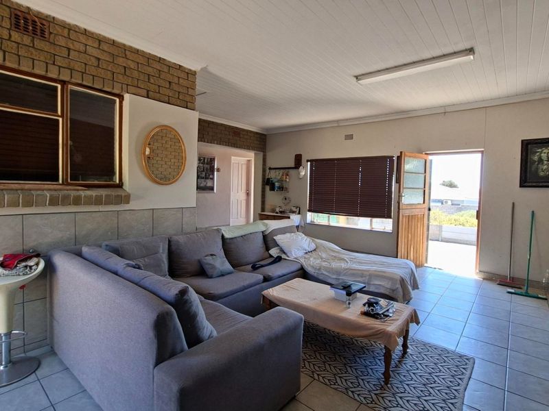 A living room featuring exposed brickwork, tiled flooring, and direct access to an outdoor area through a timber door.