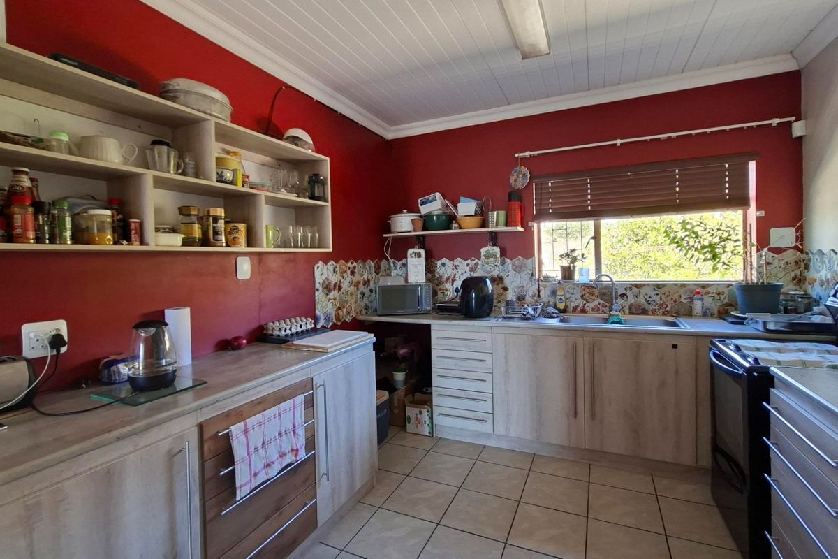 A functional kitchen featuring laminate cabinetry, tiled backsplash, and a stainless steel sink, offering a practical layout with ample storage space.