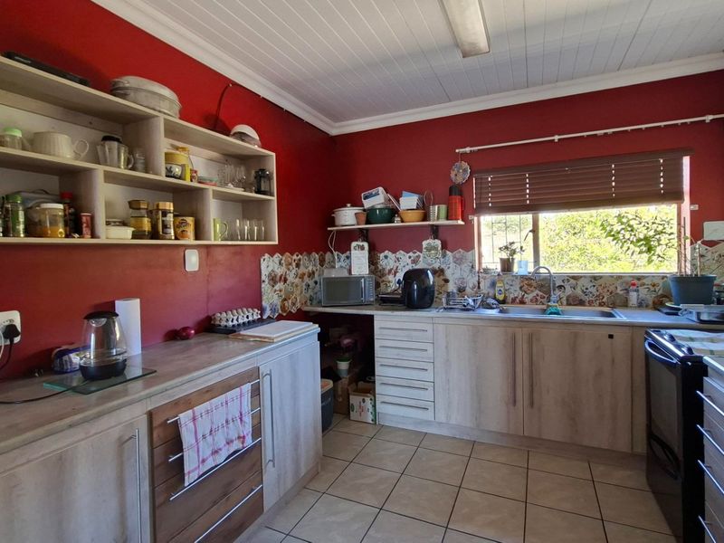 A functional kitchen featuring laminate cabinetry, tiled backsplash, and a stainless steel sink, offering a practical layout with ample storage space.