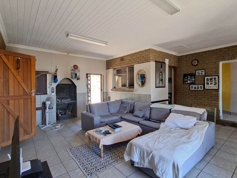 Spacious living room featuring exposed brick walls, tiled flooring, a built-in fireplace, and a timber door leading to the exterior.