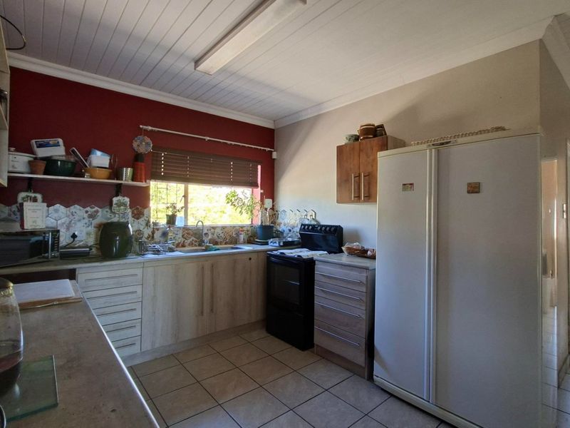 A functional kitchen featuring built-in cabinetry, tiled backsplash, and ceramic flooring, offering a practical layout with potential for modern updates.