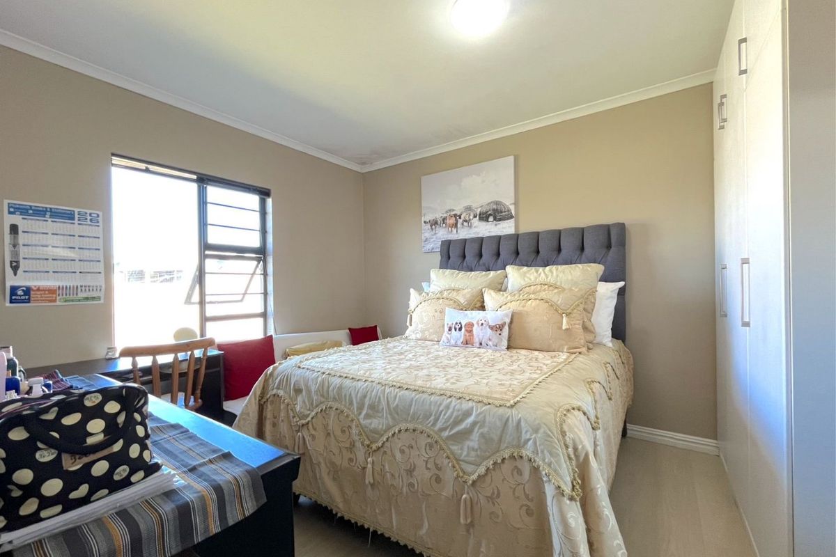 A well-maintained bedroom featuring neutral wall tones, laminate flooring, and ample built-in cupboard storage.