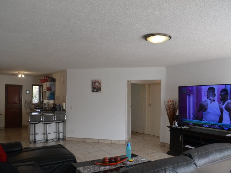 Open plan living area featuring tiled flooring, a breakfast bar, and a connected kitchen space with neutral wall finishes.