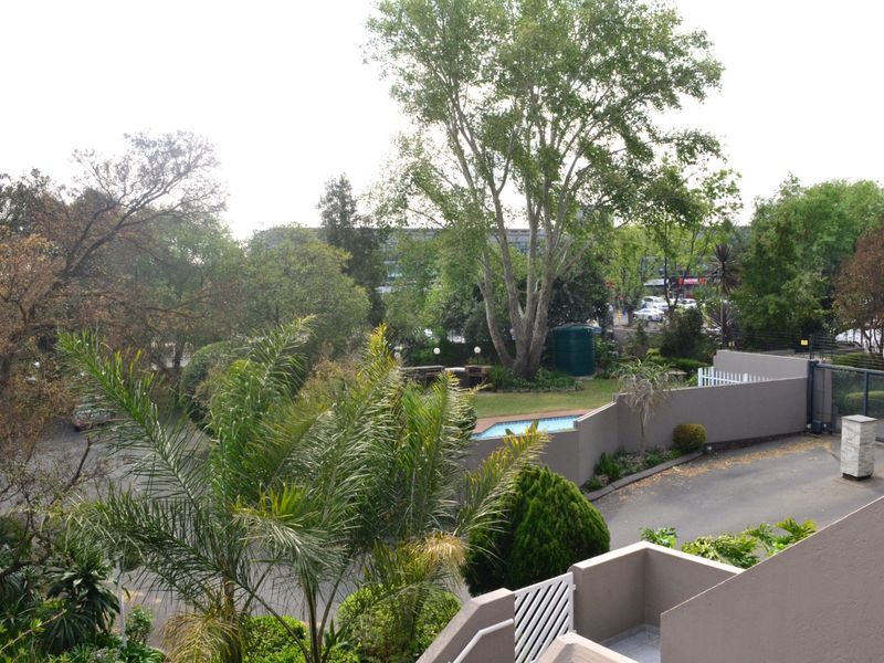 Elevated view overlooking the townhouse complex grounds, featuring a swimming pool, landscaped garden, and paved driveway area.