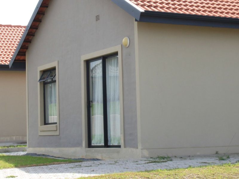 A view of the rear exterior of the house featuring terracotta roof tiles, a sliding glass door, and a casement window.