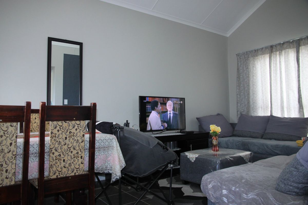 A living room area featuring vaulted ceilings and tiled flooring, providing a functional space for relaxation and dining.