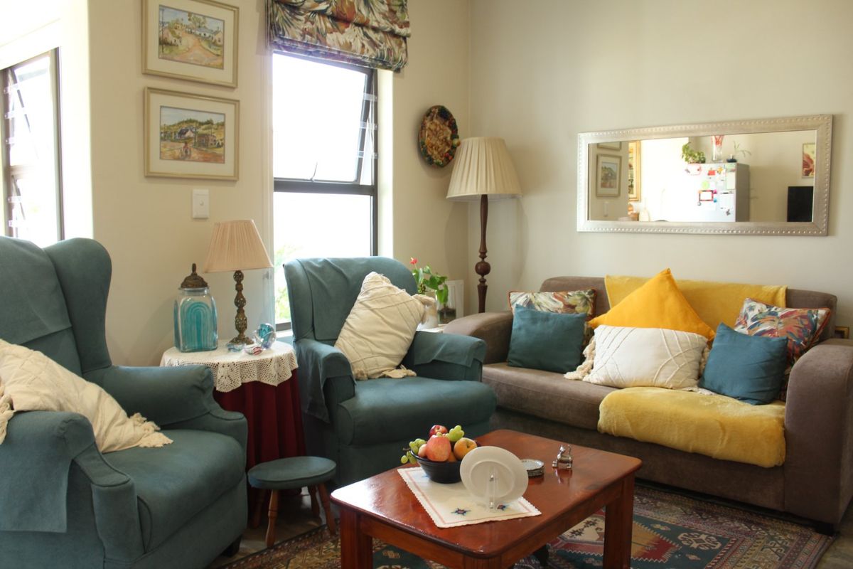 A cozy living room featuring a casement window with a roman blind, providing natural light to the seating area.