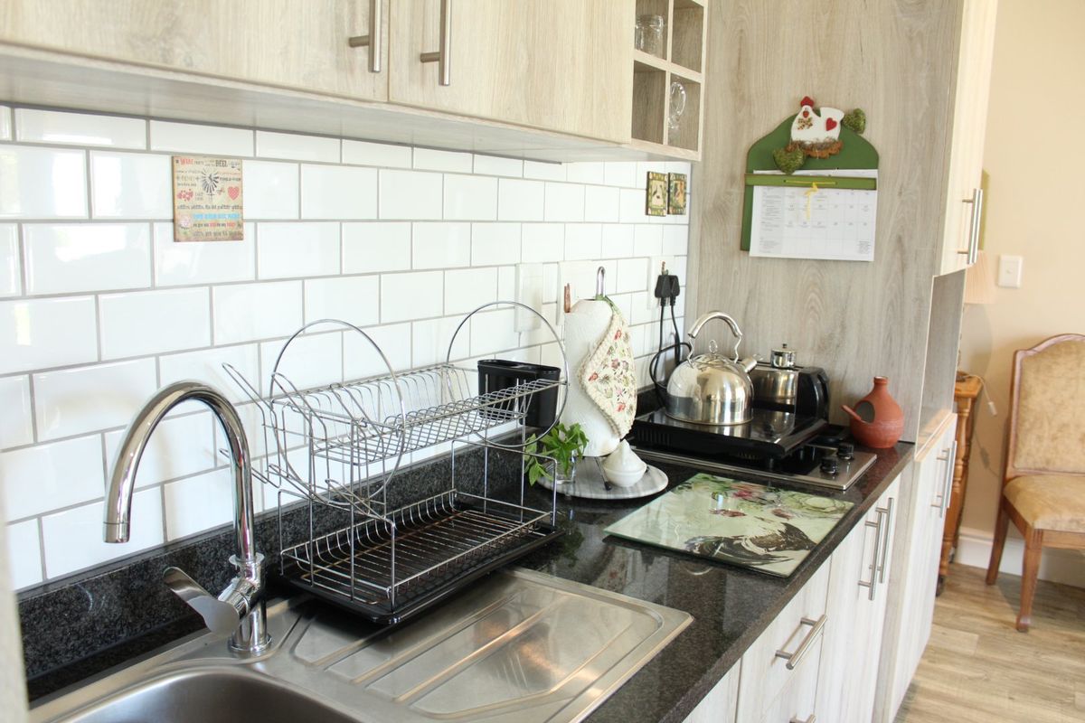 A well-maintained kitchen featuring modern subway tile backsplash, dark granite countertops, and light wood-finish cabinetry with integrated sink and hob.
