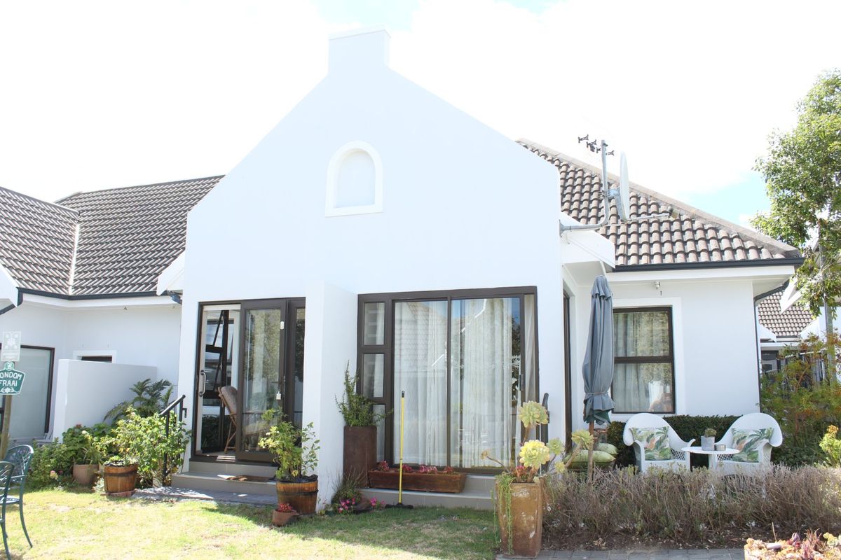 Rear view of the apartment featuring a white facade, tiled roof, and sliding glass doors leading to a small patio area.
