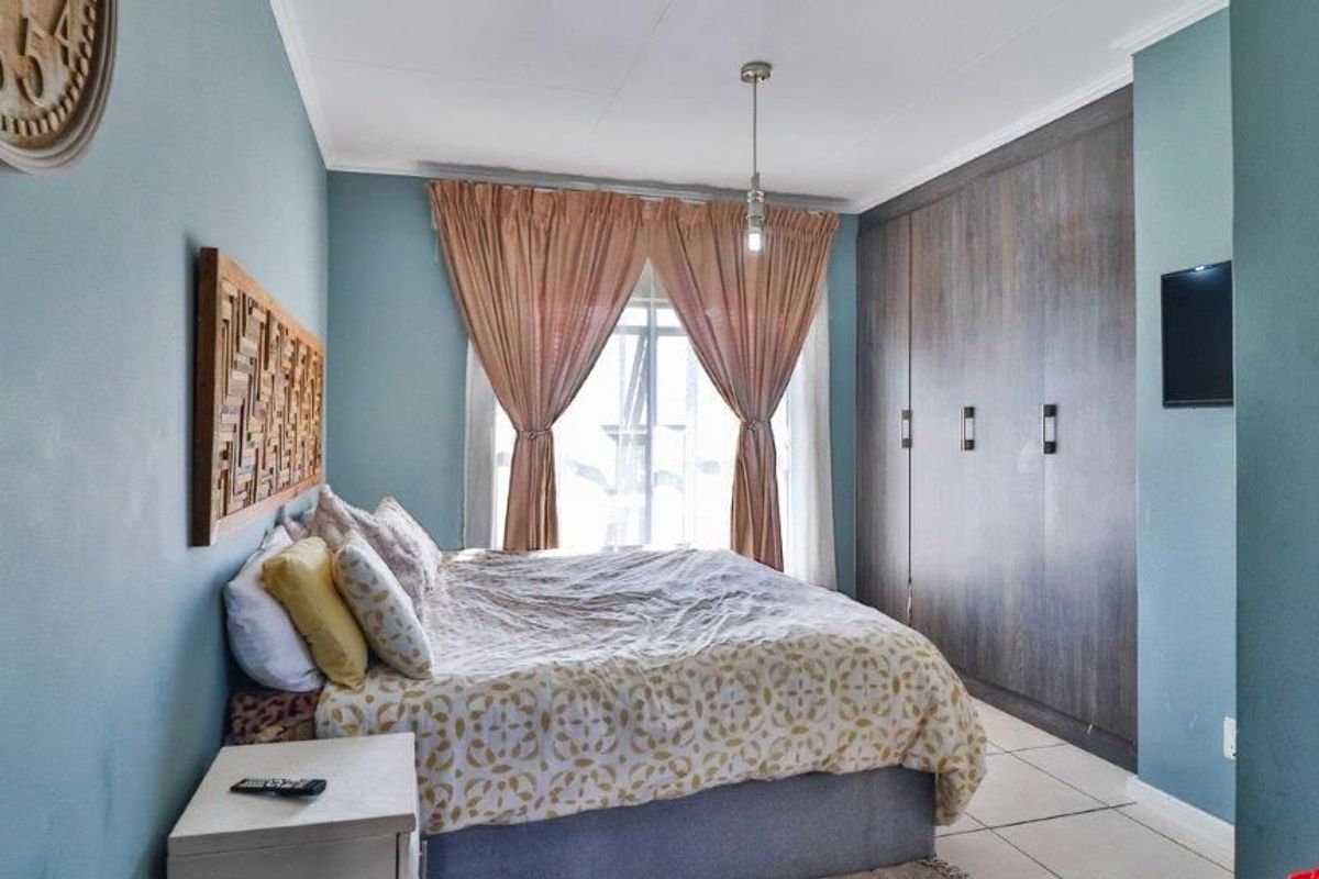 A well-maintained bedroom featuring built-in cupboards, tiled flooring, and a central pendant light, offering a comfortable and functional living space.