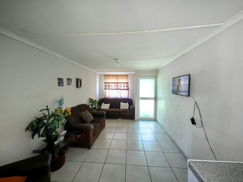 A simple living room featuring tiled flooring and a glass panel door, providing access to the exterior.