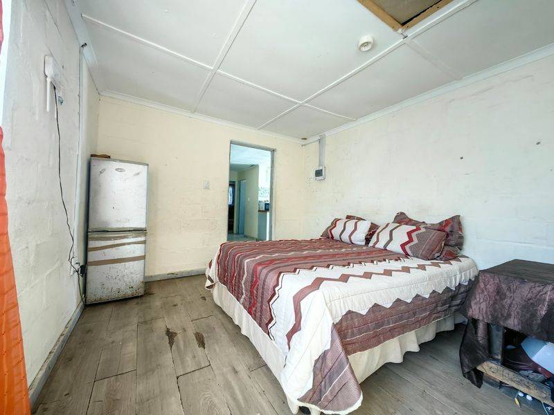 A bedroom featuring exposed blockwork walls, tiled ceiling, and timber-look flooring, requiring cosmetic updates and repairs to finishes.