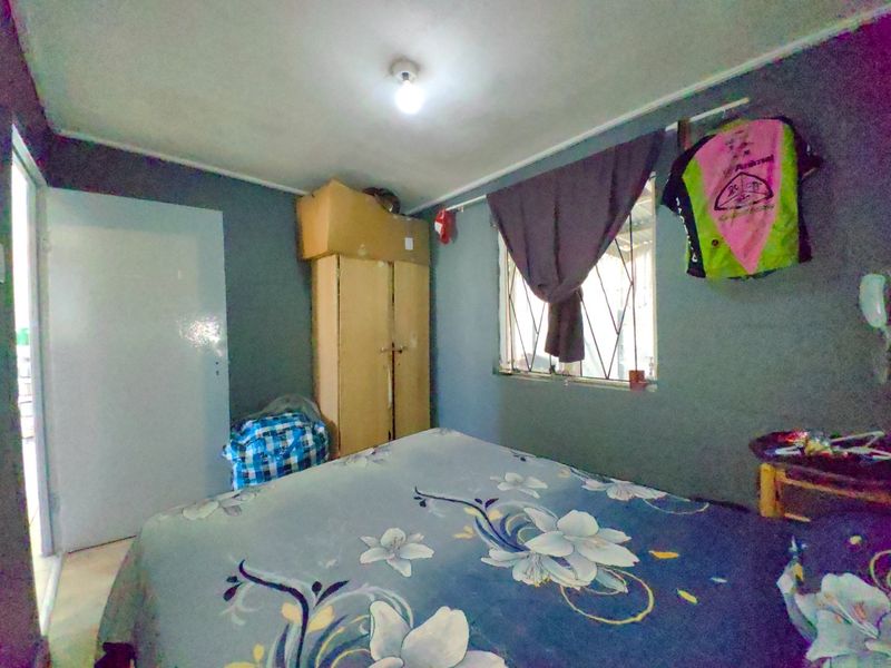 A bedroom featuring a built-in cupboard and security gate on the window, requiring cosmetic updates to improve the overall finish.
