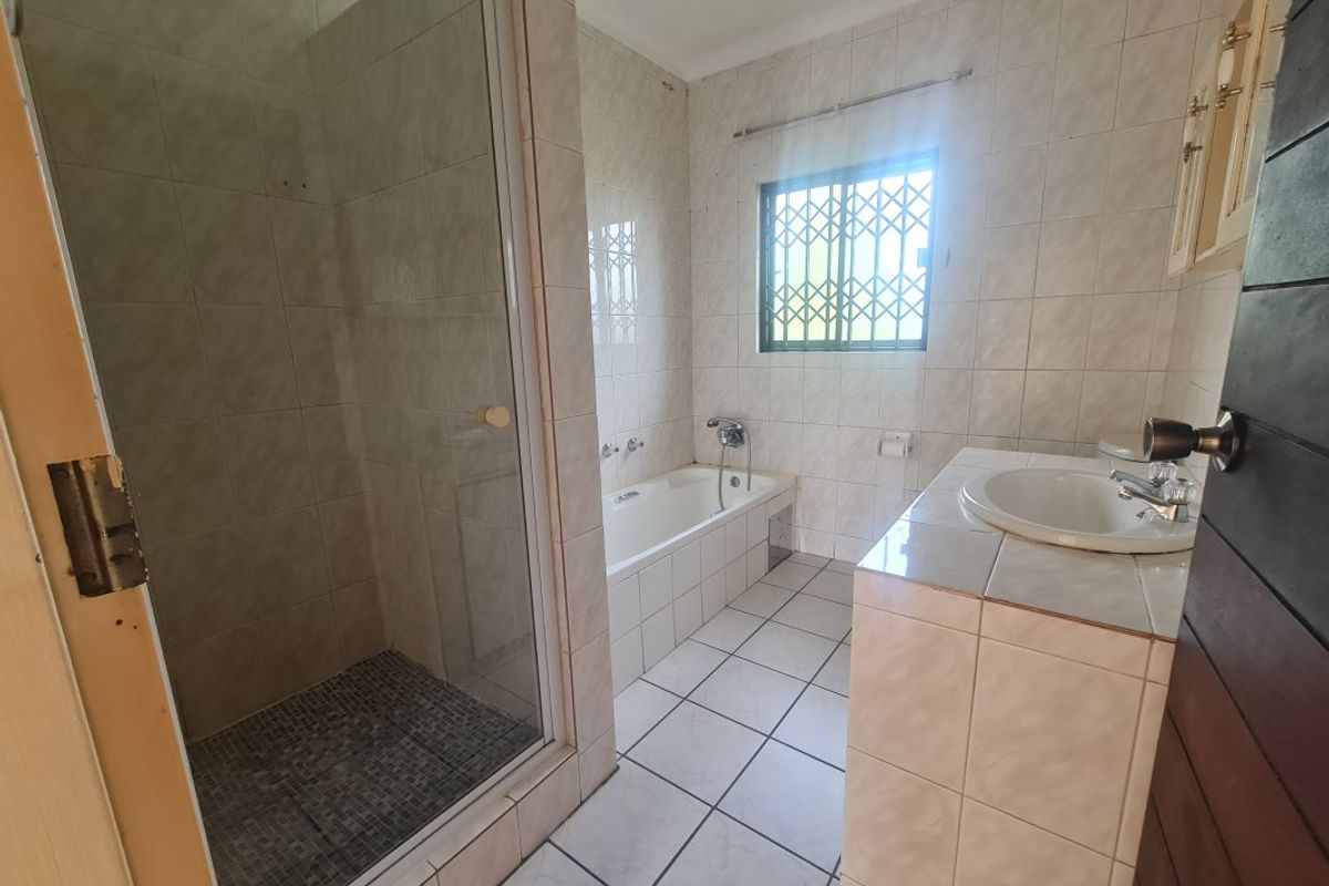 A functional bathroom featuring a separate shower enclosure, built-in bathtub, and a tiled vanity area with neutral finishes.
