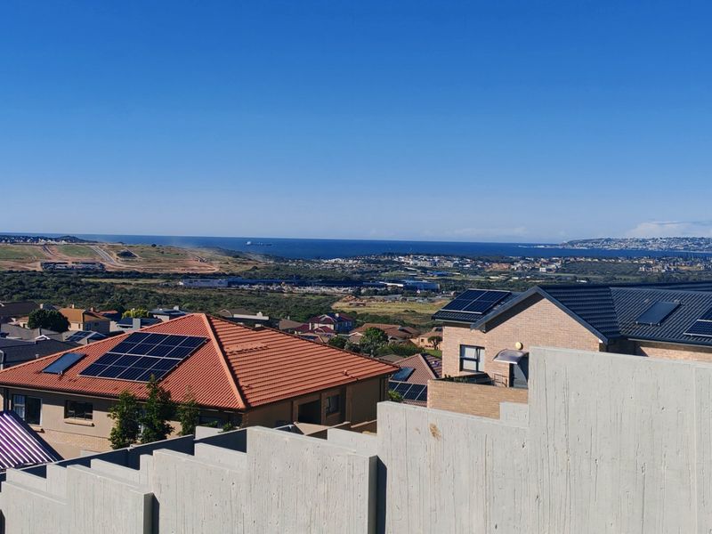 Elevated panoramic view overlooking the surrounding residential neighborhood and distant coastline, showcasing the coastal landscape and clear horizon.