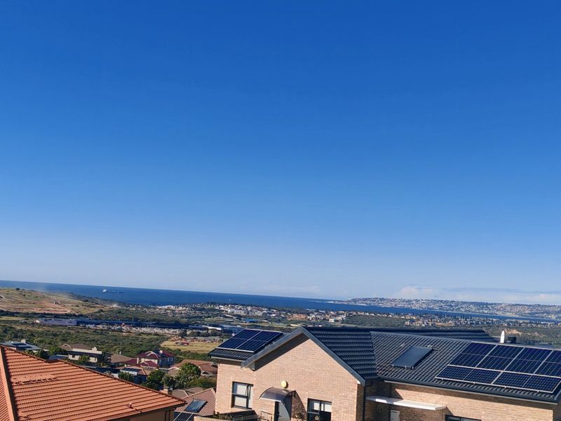 Elevated coastal view overlooking the surrounding residential area, featuring homes with installed solar panel systems under a clear blue sky.