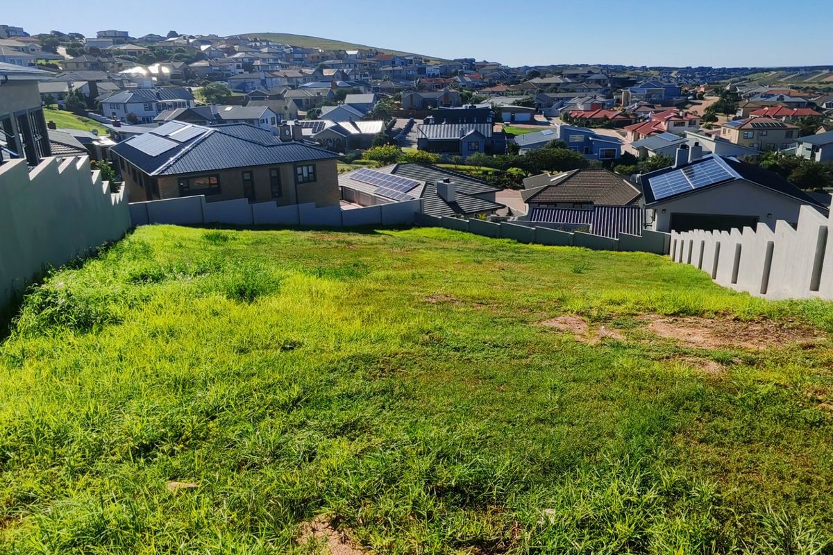 A view from a vacant residential plot overlooking a developed suburban neighborhood with established housing.