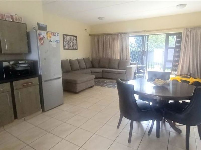 Open-plan living and kitchen area featuring tiled flooring, built-in cabinetry, and sliding glass doors providing access to the exterior.