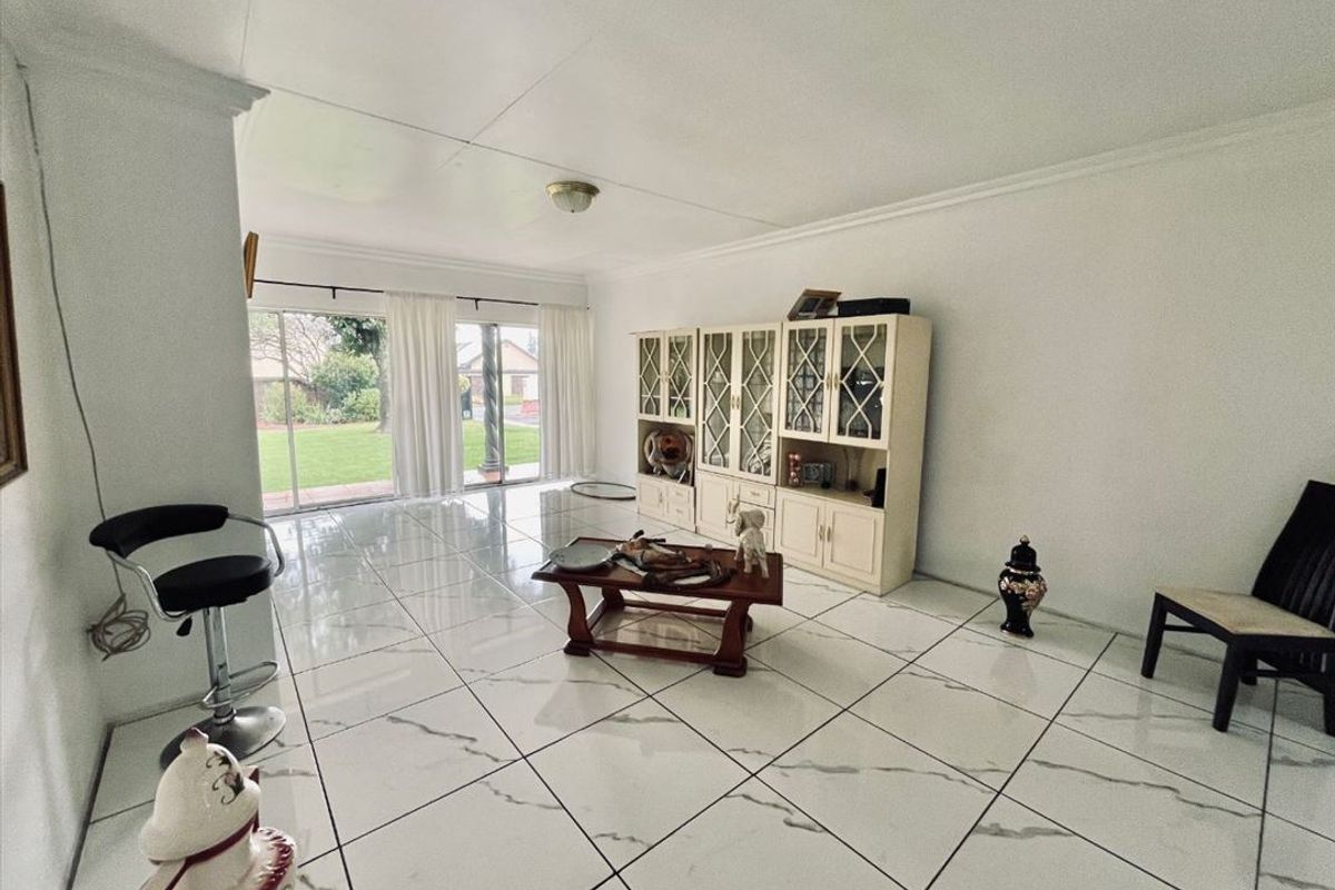 Spacious living area featuring large format marble-look floor tiles, built-in display cabinetry, and sliding glass doors providing direct access to the rear garden.