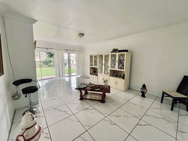Spacious living area featuring large format marble-look floor tiles, built-in display cabinetry, and sliding glass doors providing direct access to the rear garden.