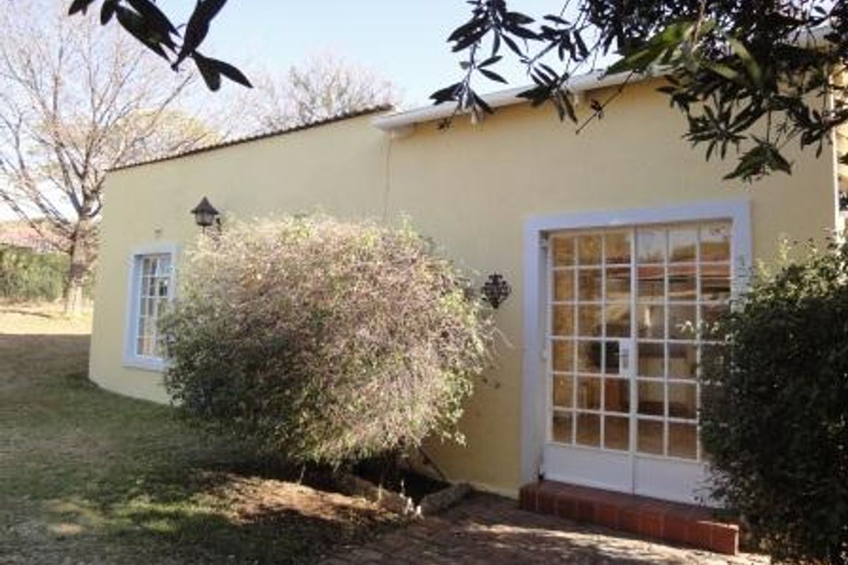 Rear exterior view of the house featuring a brick patio area, white-framed french doors, and exterior wall lighting.