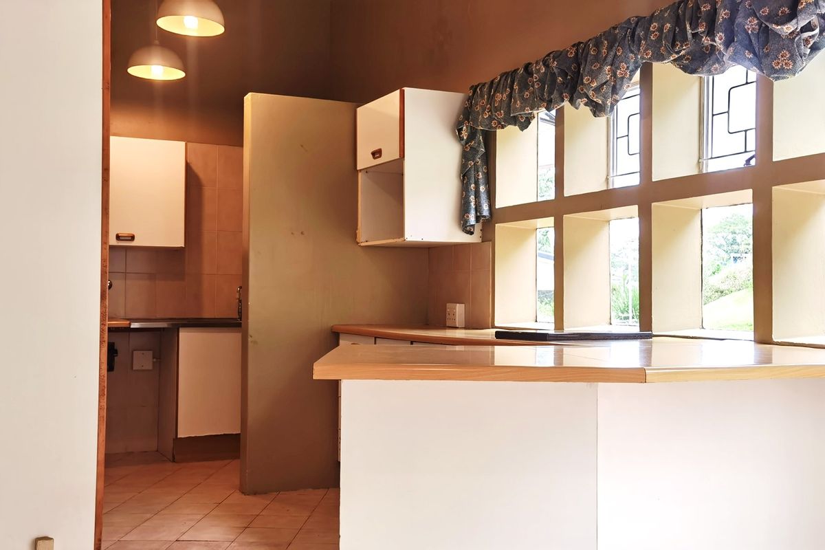 A dated kitchen featuring built-in cabinetry, laminate countertops, and a large grid-style window, offering a functional layout ready for modern renovation.