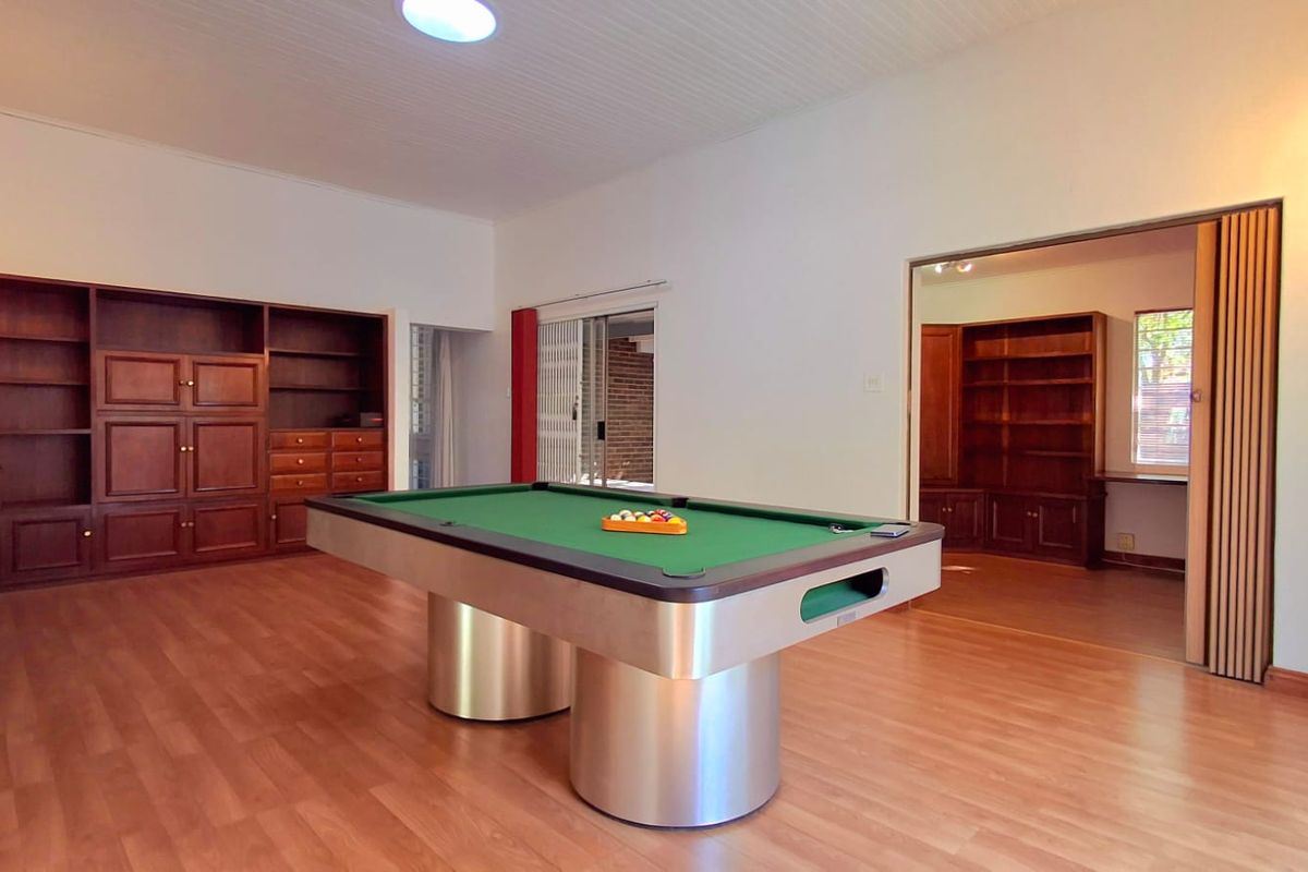 Spacious living area featuring built-in wooden cabinetry, laminate flooring, and a folding door leading to an adjacent room.