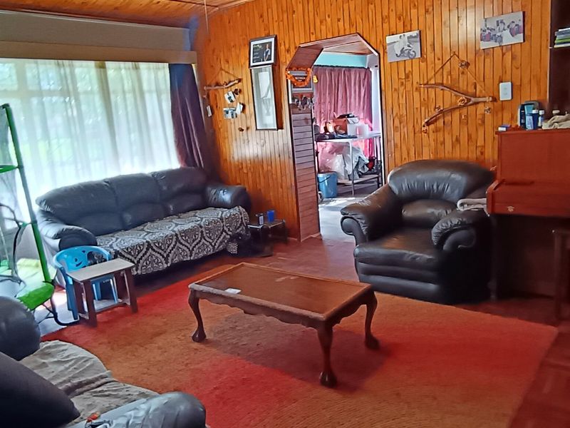 A living room featuring traditional timber wall paneling, a timber ceiling, and parquet flooring, with an archway leading to an adjacent space.