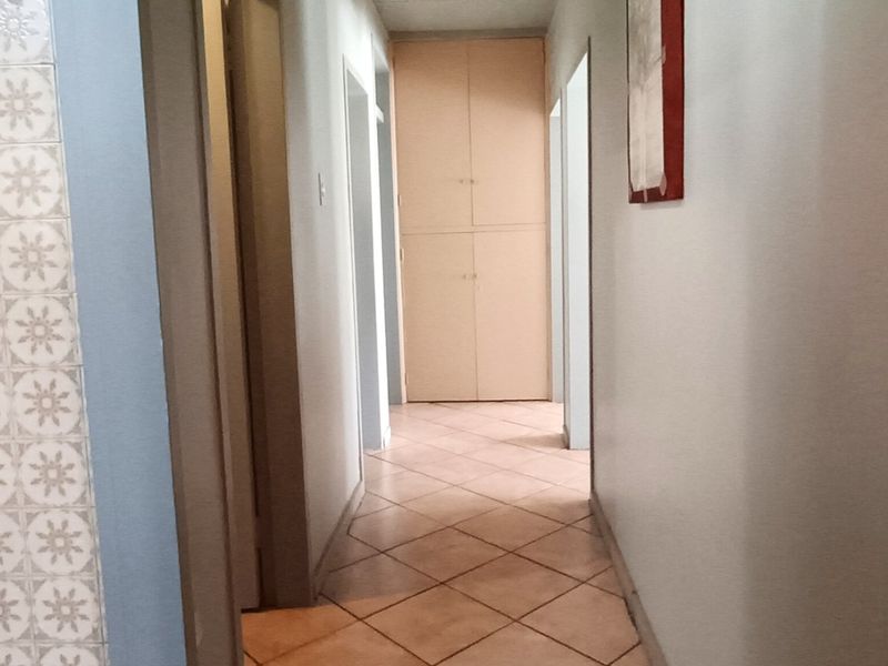 A functional hallway featuring tiled flooring and built-in storage cupboards, providing access to various rooms within the home.