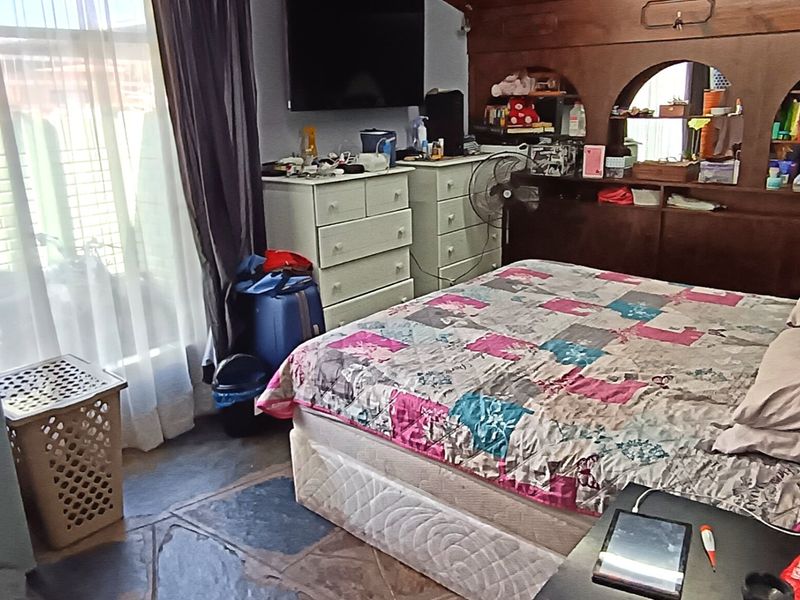 A bedroom featuring stone flooring, a built-in wooden headboard with shelving, and a sliding glass door providing natural light.