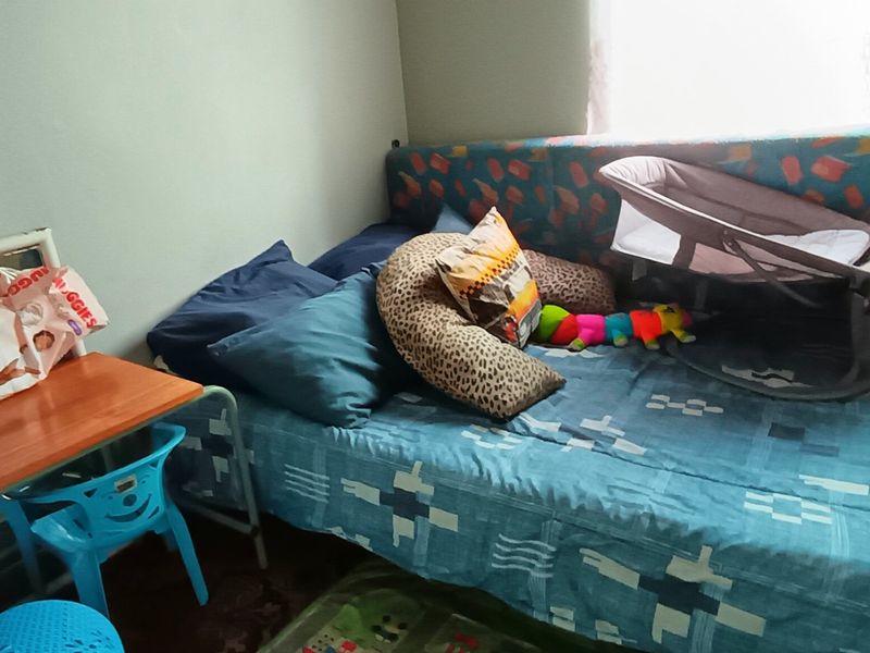 A bedroom space featuring a single bed and window, currently utilized as a nursery area.