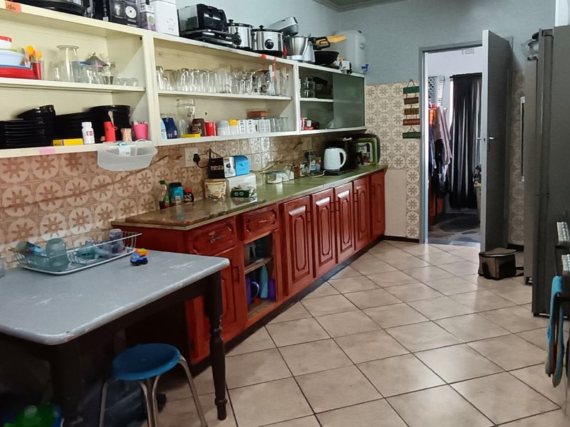 A functional kitchen featuring built-in wooden cabinetry, tiled backsplash, and tiled flooring, offering a traditional layout with ample storage space.