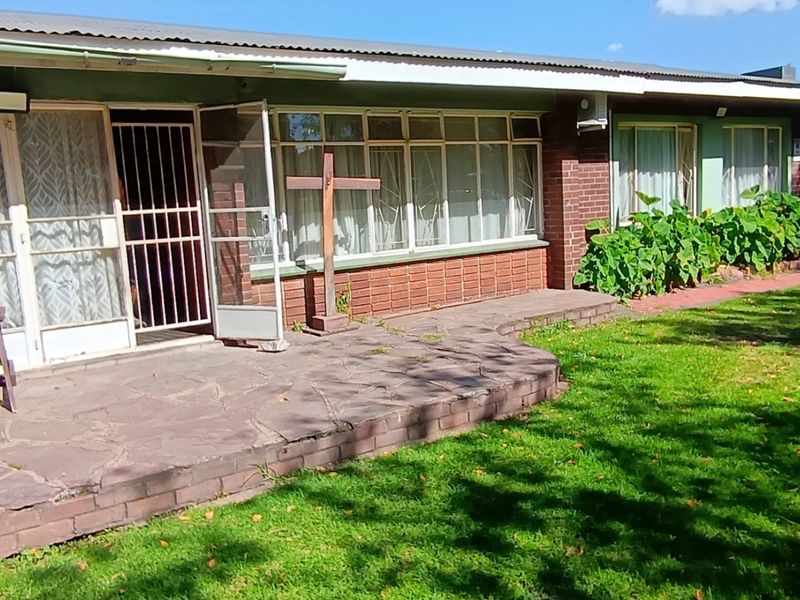 A covered patio area featuring flagstone paving and brick exterior walls, providing direct access to the garden through sliding glass doors.
