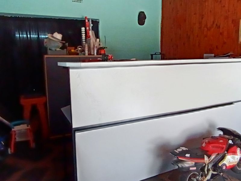 A home bar area featuring a modern white built-in counter set against a wood-paneled wall.