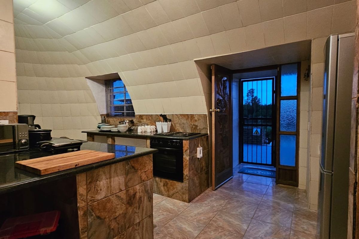 A unique kitchen featuring a vaulted tiled ceiling, granite countertops, built-in oven, and direct access to an exterior security gate.