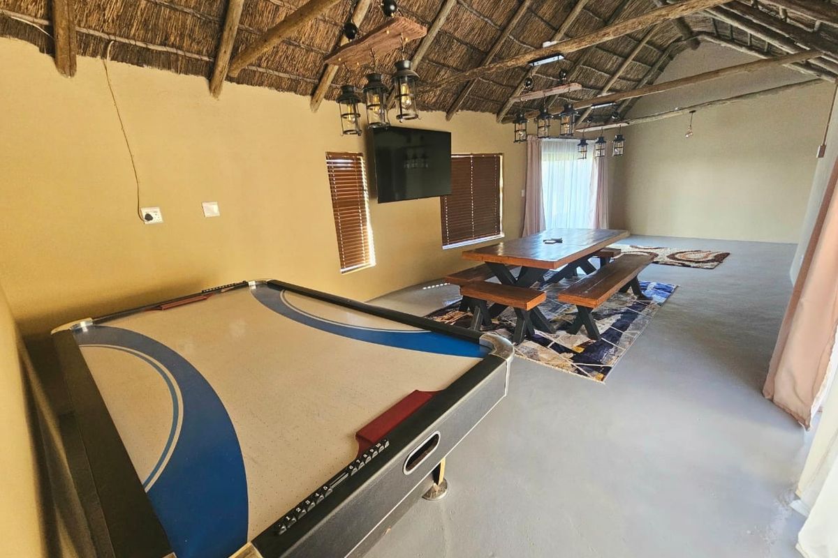Spacious living area featuring a traditional thatched roof with exposed timber rafters and durable concrete flooring, offering a rustic and open entertainment space.