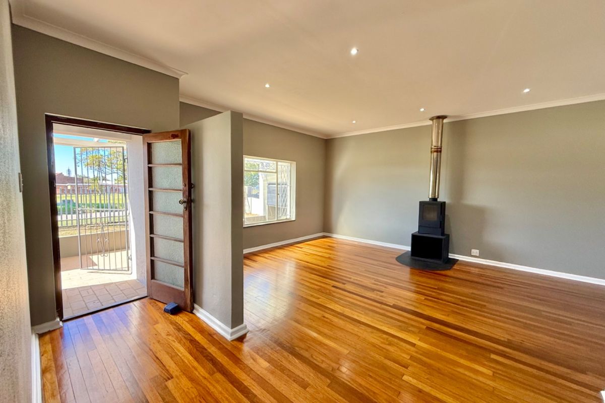 Spacious living room featuring polished hardwood flooring, a modern freestanding fireplace, and direct access to an outdoor patio area.