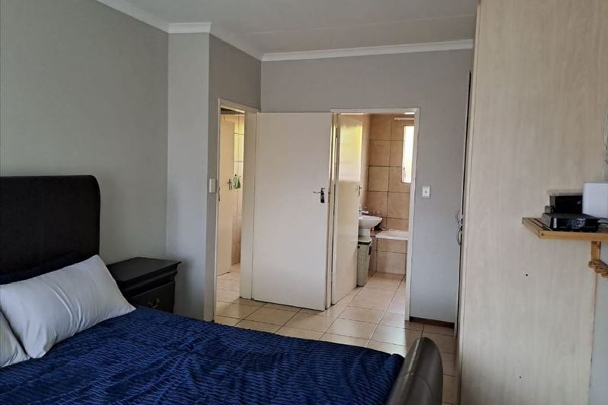 A bedroom featuring built-in cupboards, tiled flooring, and direct access to an en-suite bathroom.