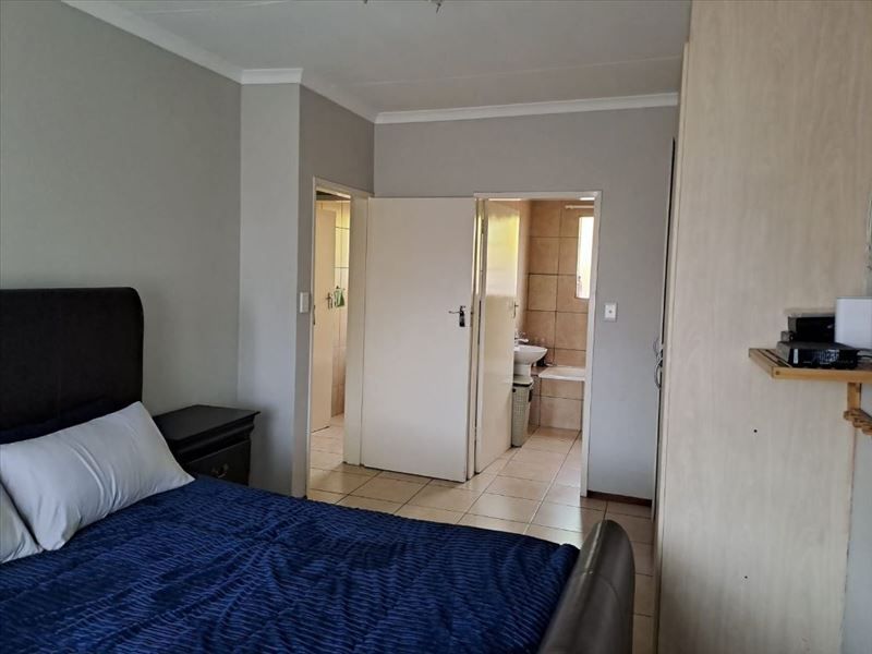 A bedroom featuring built-in cupboards, tiled flooring, and direct access to an en-suite bathroom.
