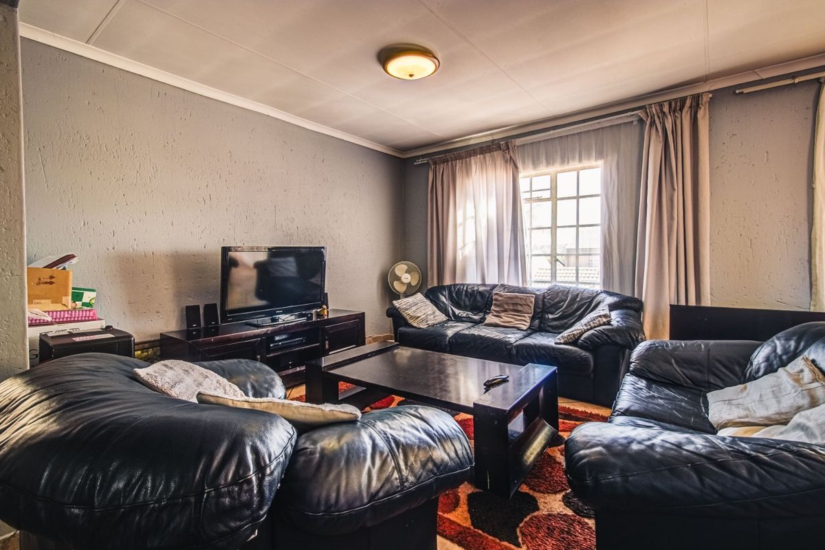 A living room featuring textured walls, a central ceiling light fixture, and a window with curtain tracks.