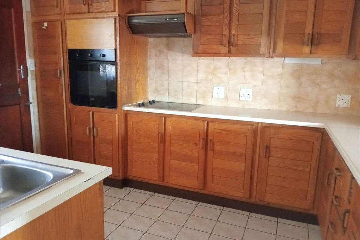 A functional kitchen featuring traditional wooden cabinetry, built-in oven and hob, tiled splashbacks, and durable ceramic flooring.