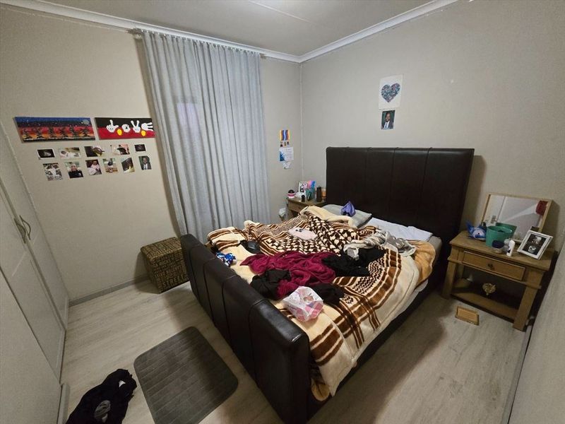 A functional bedroom featuring light-toned laminate flooring and a built-in wardrobe, providing a neutral foundation for personal styling.