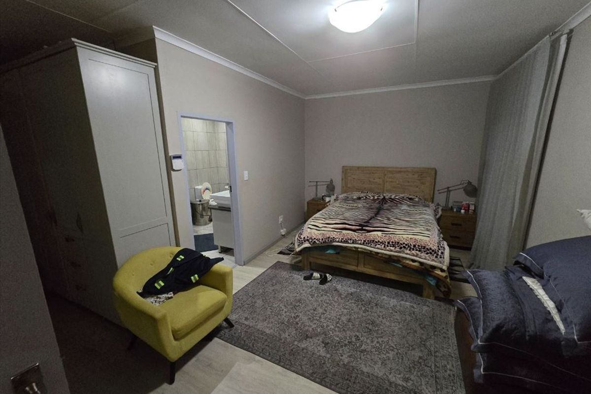 A bedroom featuring laminate flooring, built-in wardrobe, and direct access to an en-suite bathroom.