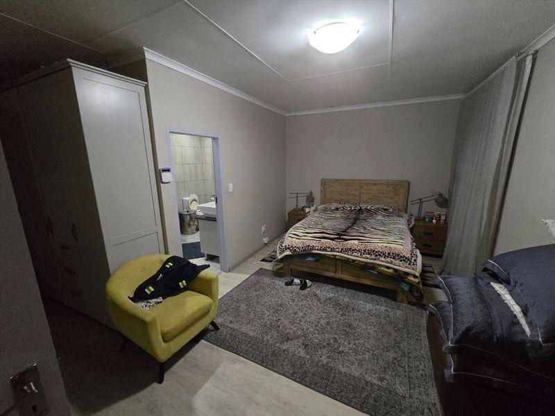 A bedroom featuring laminate flooring, built-in wardrobe, and direct access to an en-suite bathroom.