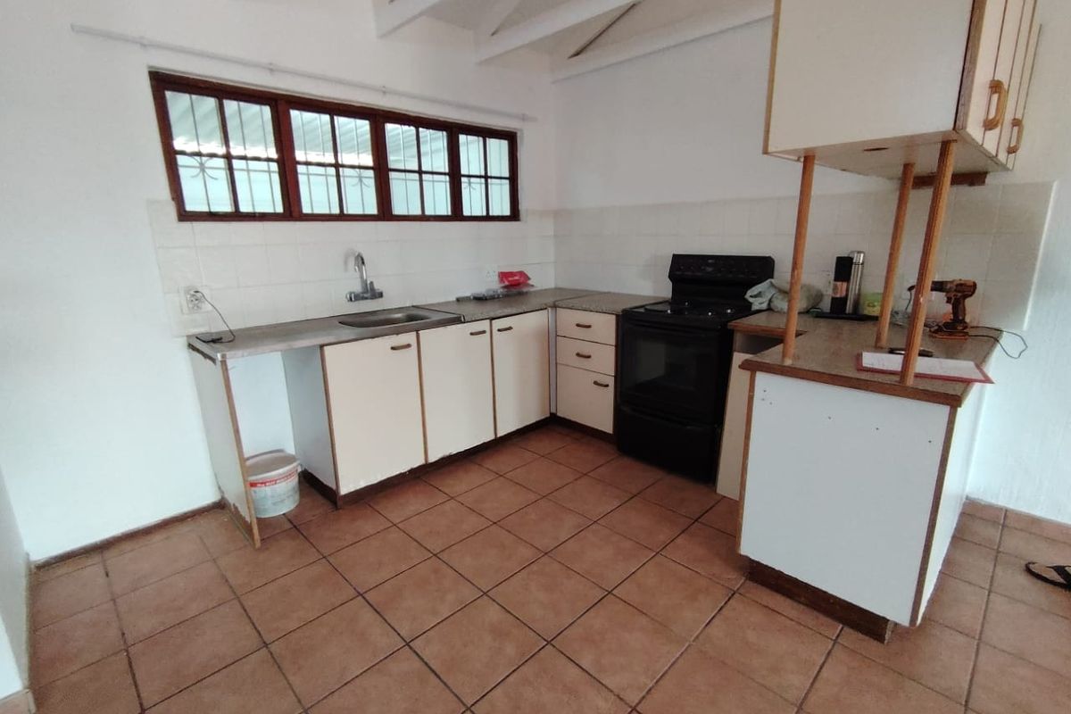 A dated kitchen featuring tiled flooring, laminate cabinetry, and a freestanding stove, offering a functional layout with potential for modernization.