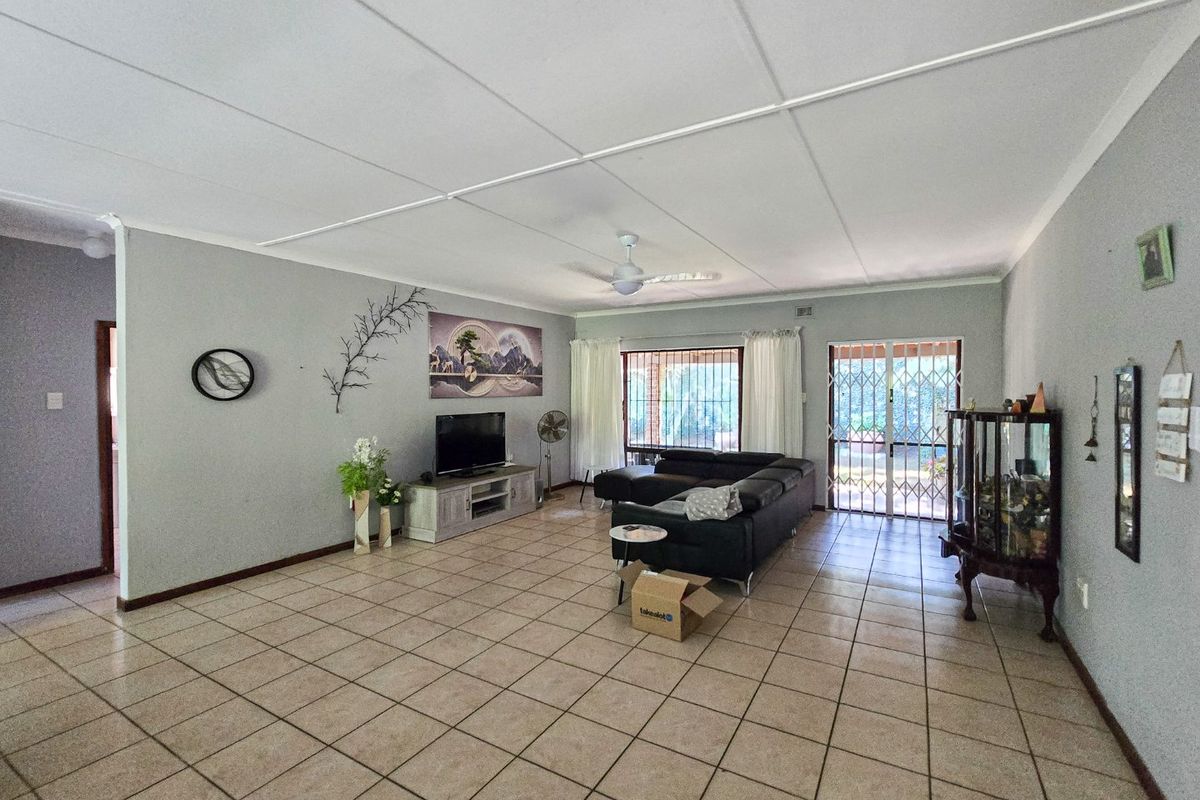 Spacious living room featuring neutral tiled flooring, a ceiling fan, and direct access to the outdoor area through a secure sliding door.