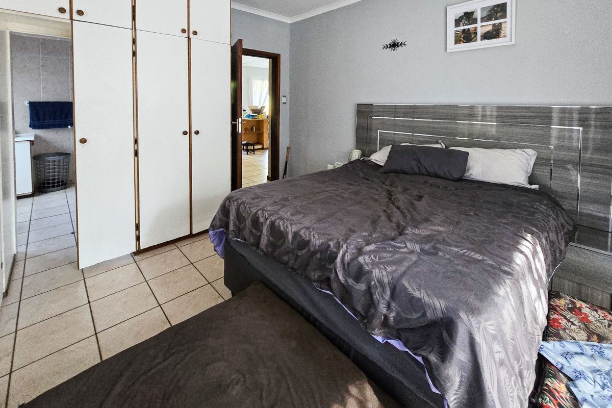 A bedroom featuring built-in cupboards, tiled flooring, and a coved ceiling, with an adjoining room visible through the doorway.